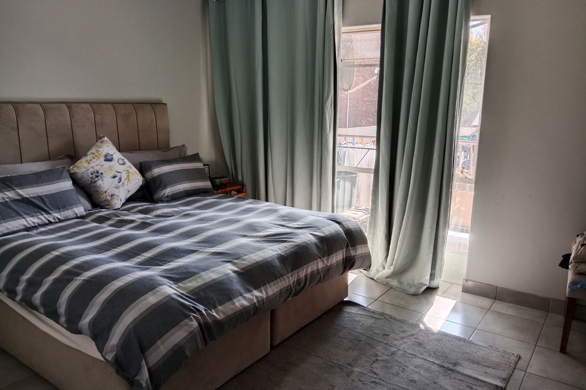 A bedroom featuring tiled flooring and a sliding glass door that provides access to an outdoor patio area.