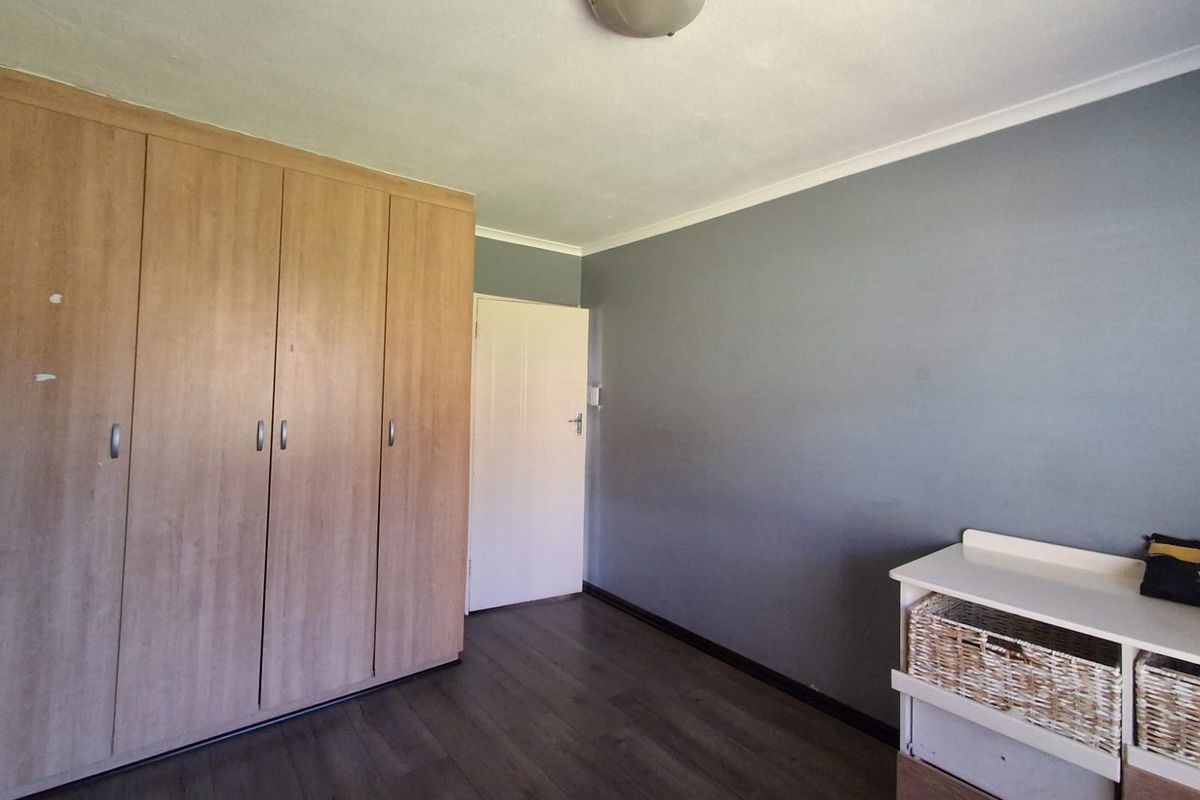 A bedroom featuring laminate flooring and built-in wooden cupboards, offering a neutral base for personalization.