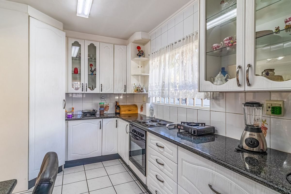 A functional kitchen featuring white cabinetry, dark granite countertops, tiled backsplash, and built-in oven with hob.