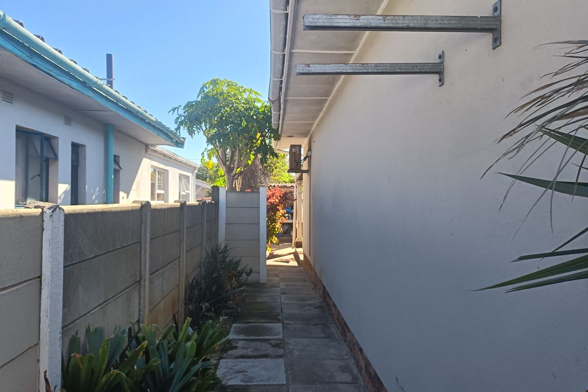 A side exterior walkway featuring a paved path, precast concrete boundary wall, and external wall-mounted brackets.