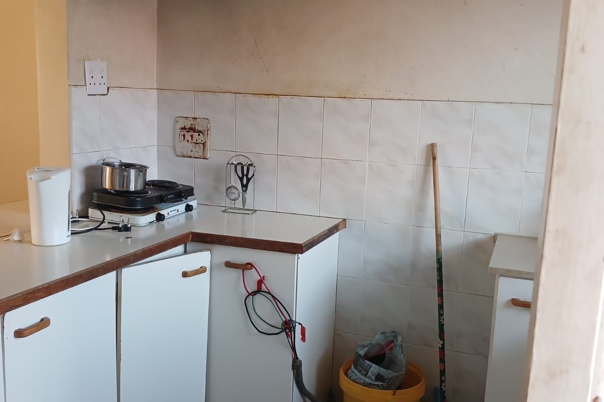 A compact kitchen featuring tiled splashbacks, laminate countertops, and built-in cabinetry, currently requiring maintenance and cosmetic updates to improve functionality and aesthetic appeal.