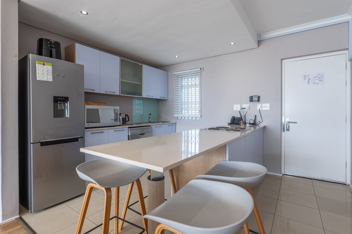 Modern kitchen featuring sleek cabinetry, a central island with stone countertops, recessed lighting, and tiled flooring in an open-plan layout.