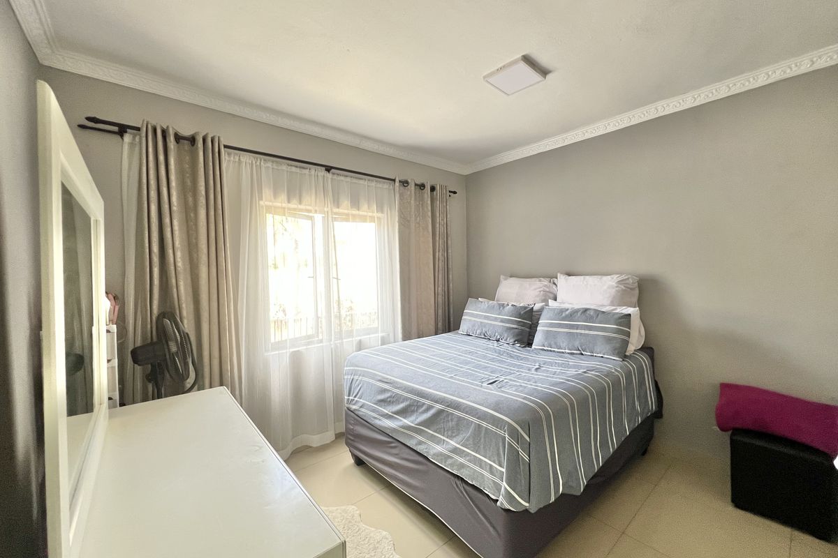 A well-lit bedroom featuring tiled flooring and decorative crown molding, providing a neutral foundation for personal styling.