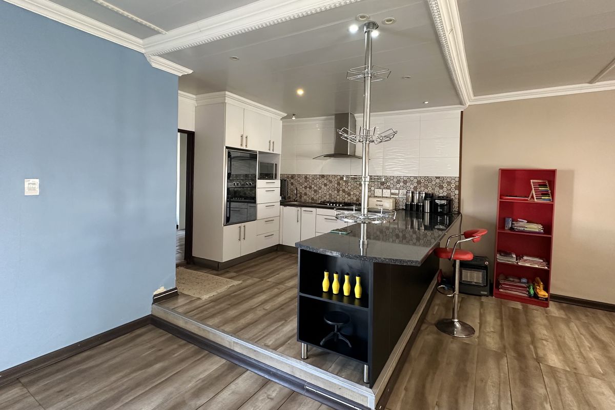 Modern kitchen featuring a central island with granite countertops, built-in oven, gas hob, and extractor fan, complemented by recessed lighting and crown molding.