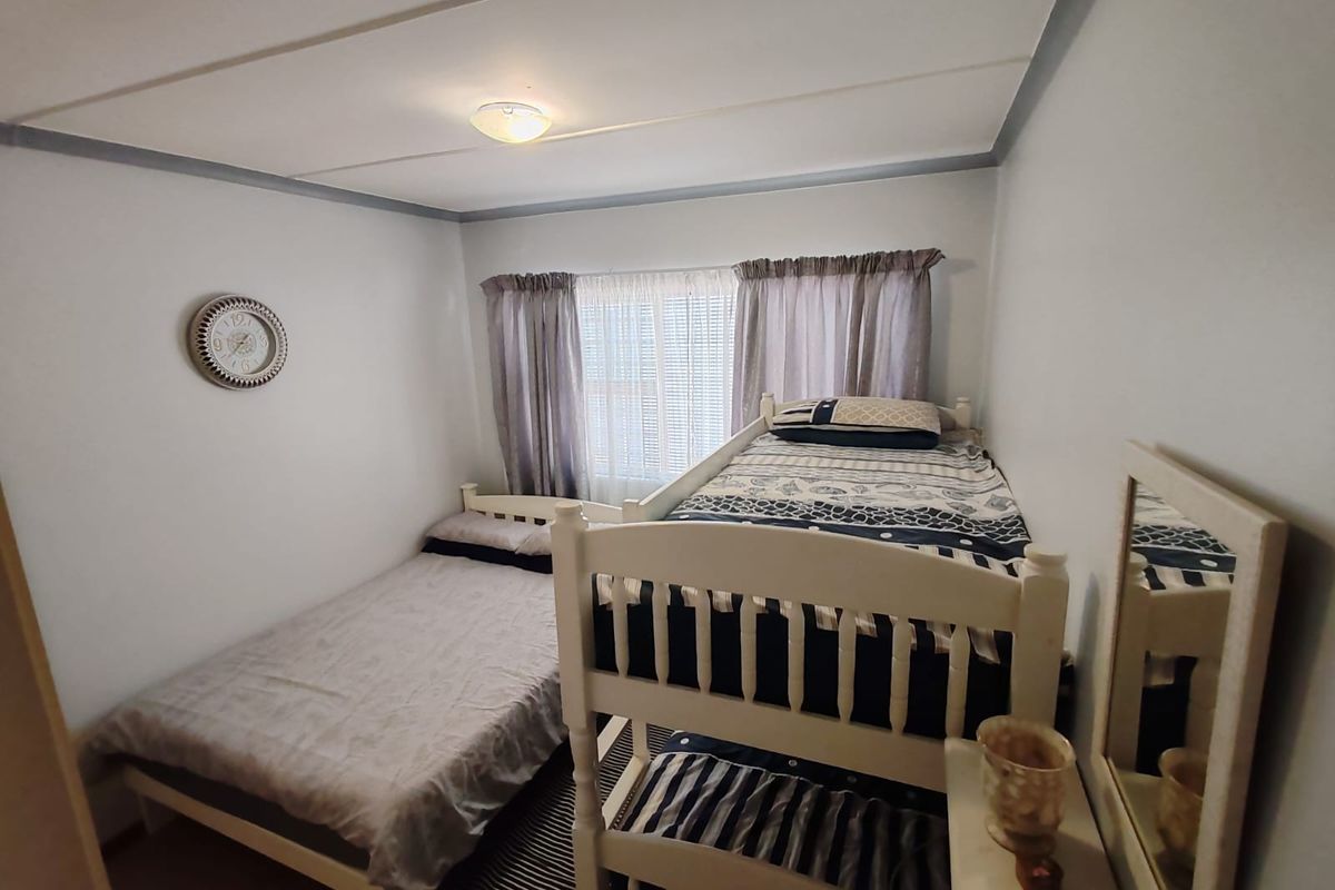 A functional bedroom featuring neutral wall finishes, a central ceiling light, and window treatments, providing a practical space for sleeping arrangements.