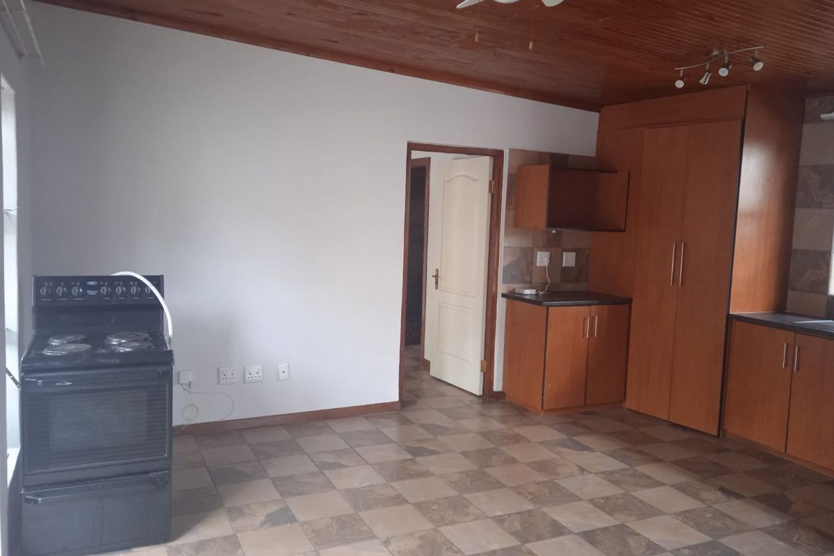 A functional kitchen featuring wooden ceilings, tiled flooring, built-in cabinetry, and a freestanding stove, offering a practical layout ready for updates.