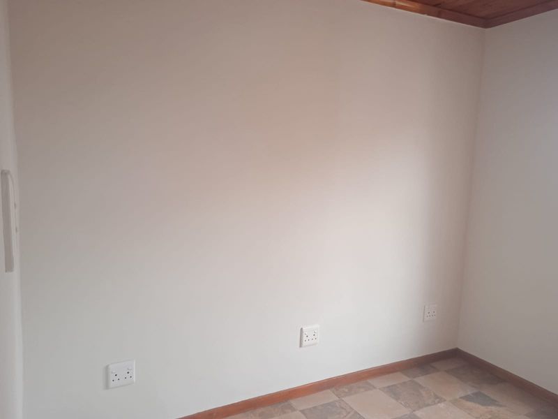 An empty bedroom featuring tiled flooring, timber ceiling trim, and multiple electrical sockets on the wall.