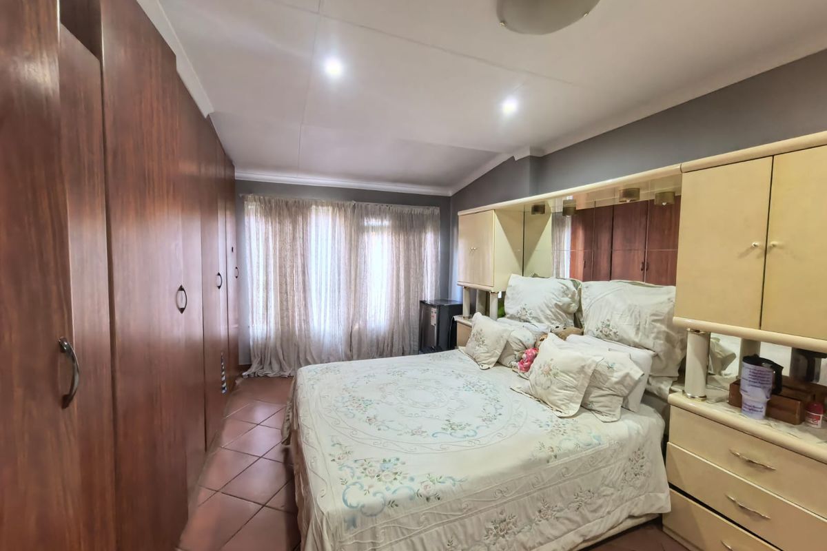 A bedroom featuring extensive built-in wooden cupboards, tiled flooring, and recessed ceiling lighting, offering a functional and well-utilized space.