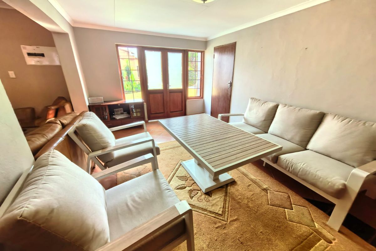 A living room featuring tiled flooring, wooden french doors providing natural light, and neutral wall finishes, offering a functional space for relaxation.
