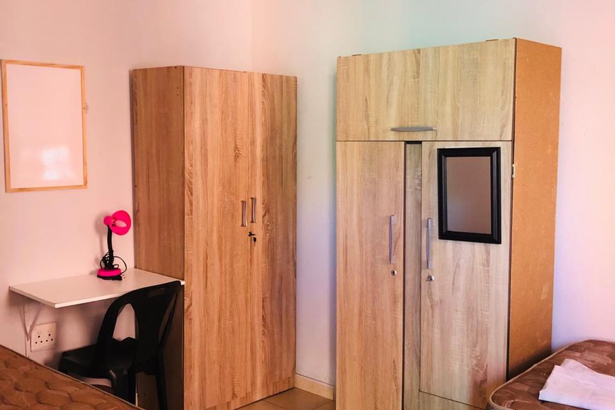 A functional bedroom featuring tiled flooring and a simple ceiling light fixture, providing a basic living space.