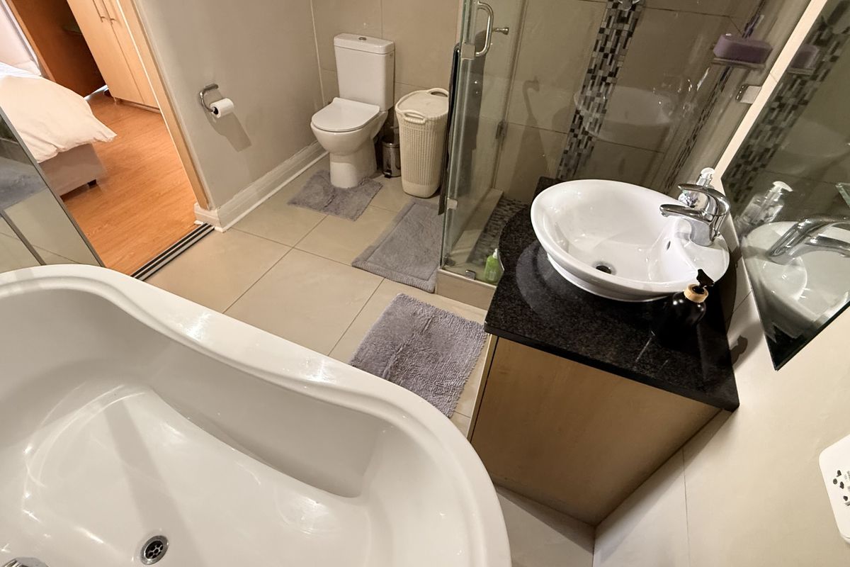 A modern bathroom featuring a freestanding bathtub, a glass-enclosed shower, a vanity with a vessel sink, and a toilet.