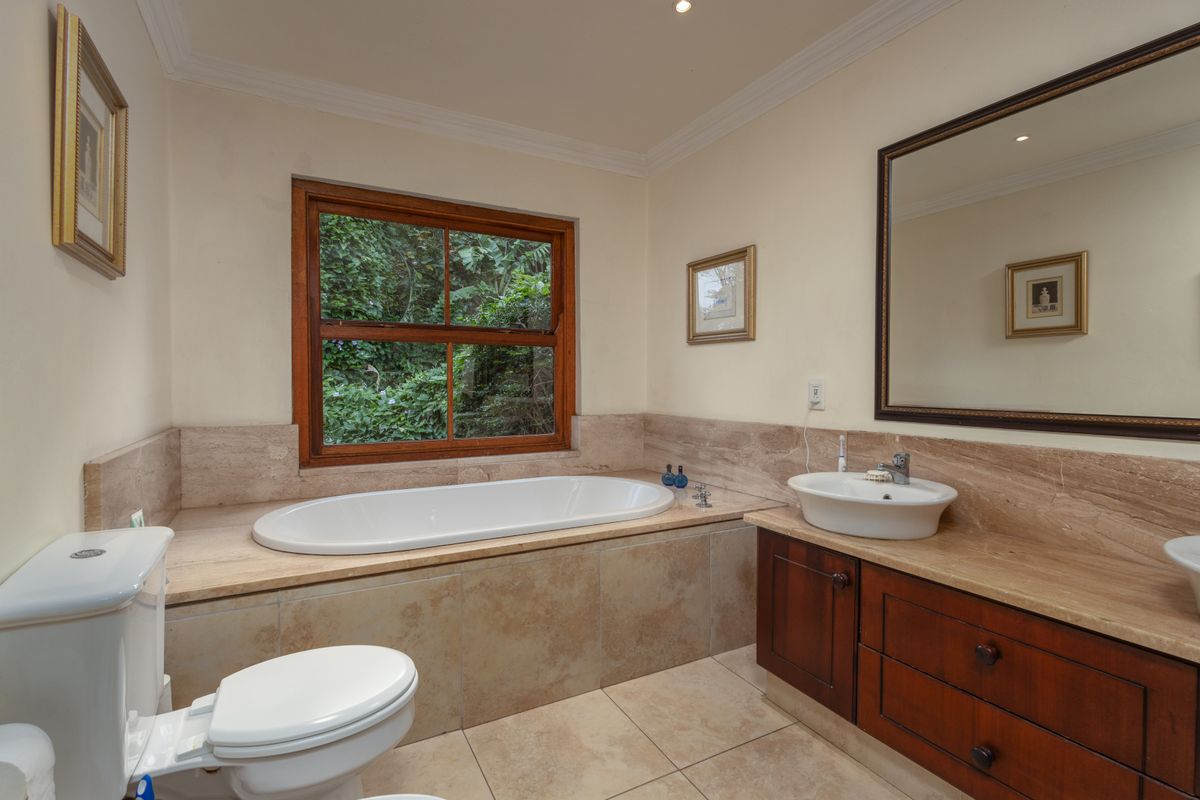 A well-maintained bathroom featuring a built-in bathtub with stone surround, a wooden vanity with a vessel sink, and tiled flooring.