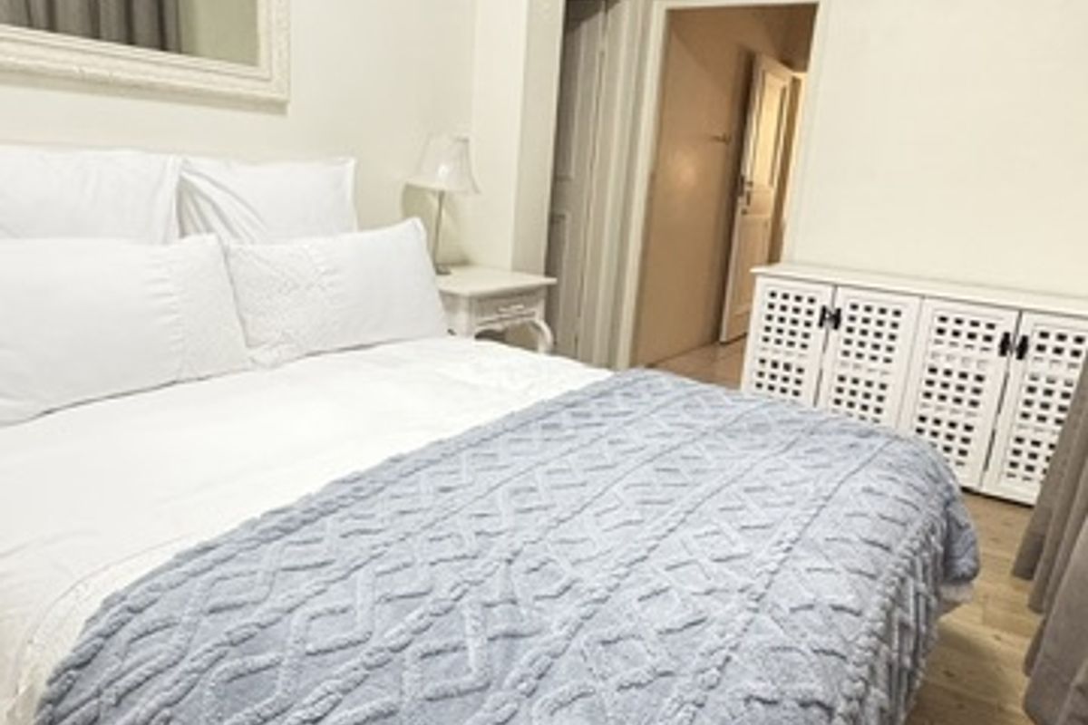 A bedroom featuring laminate flooring, coved ceilings, and built-in storage cabinetry, offering a functional space with neutral finishes.