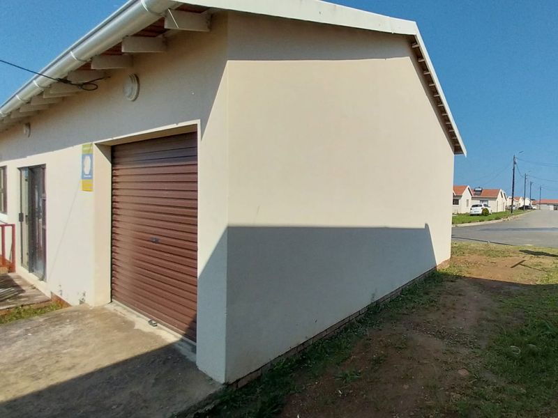 Side view of a residential garage featuring a brown roller shutter door, concrete apron, and exposed roof rafters.