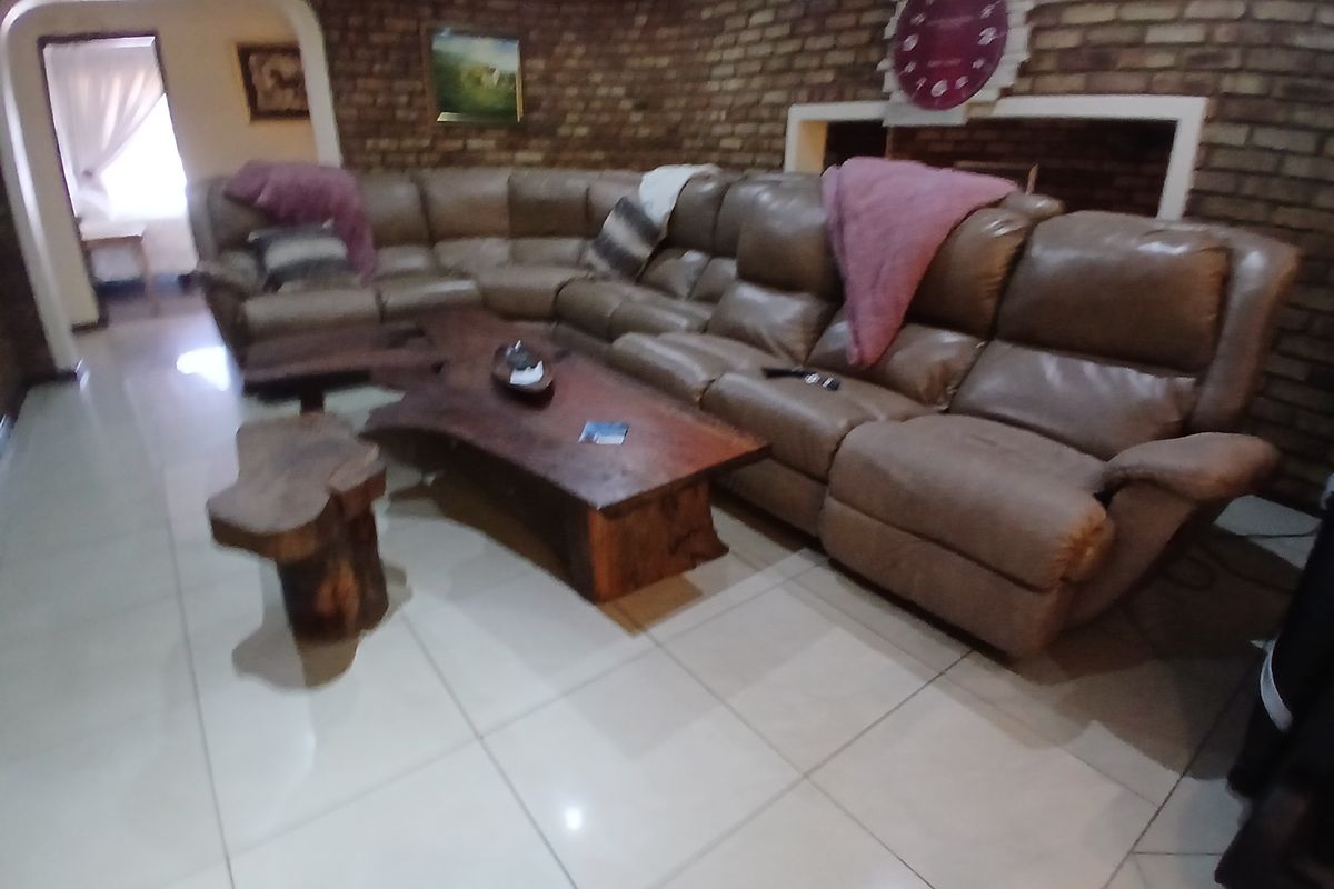A living room featuring exposed brick walls, large format floor tiles, and an arched entryway leading to an adjacent space.