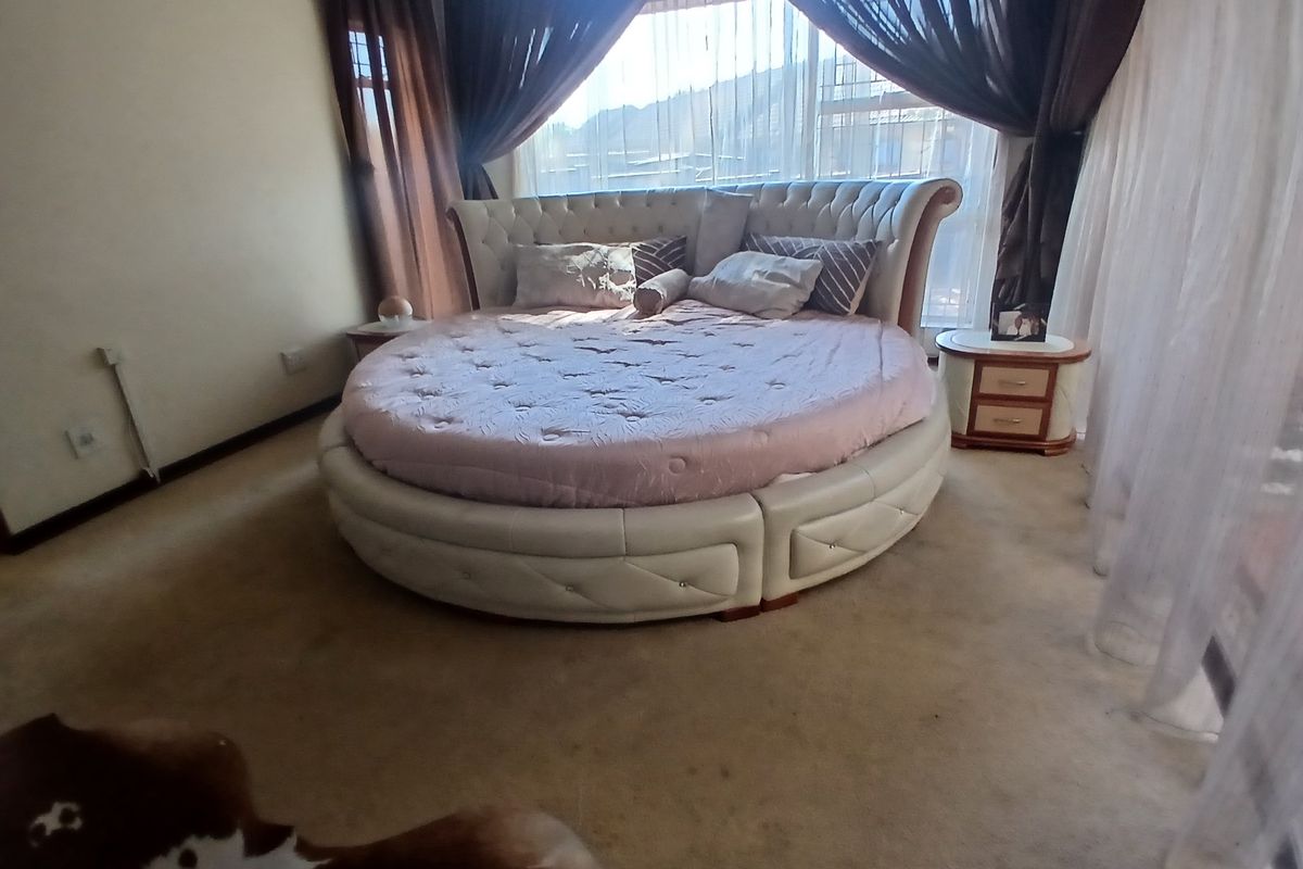 A spacious bedroom featuring carpeted flooring and a large window with curtains, providing natural light and access to the exterior.