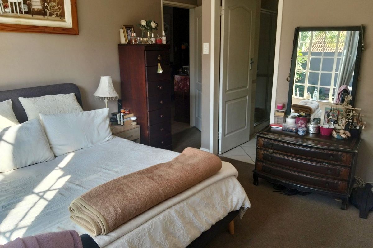 A carpeted bedroom featuring neutral wall tones and direct access to an adjoining bathroom area.