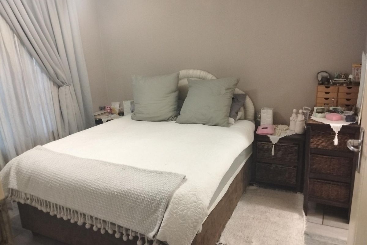 A functional bedroom featuring tiled flooring and neutral wall tones, providing a comfortable and well-maintained space.