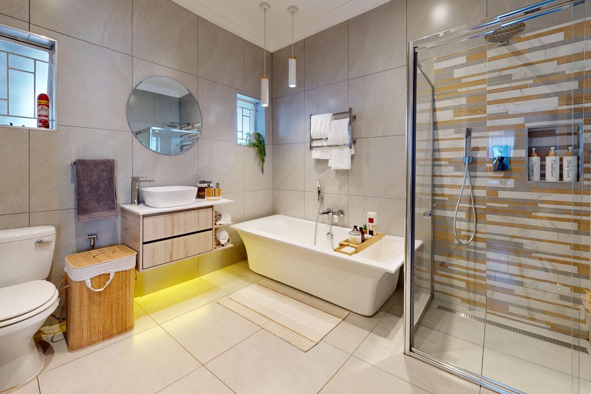 Modern, well-appointed bathroom featuring a freestanding bathtub, a spacious walk-in shower with decorative tiling, and a sleek wall-mounted vanity with a vessel sink.