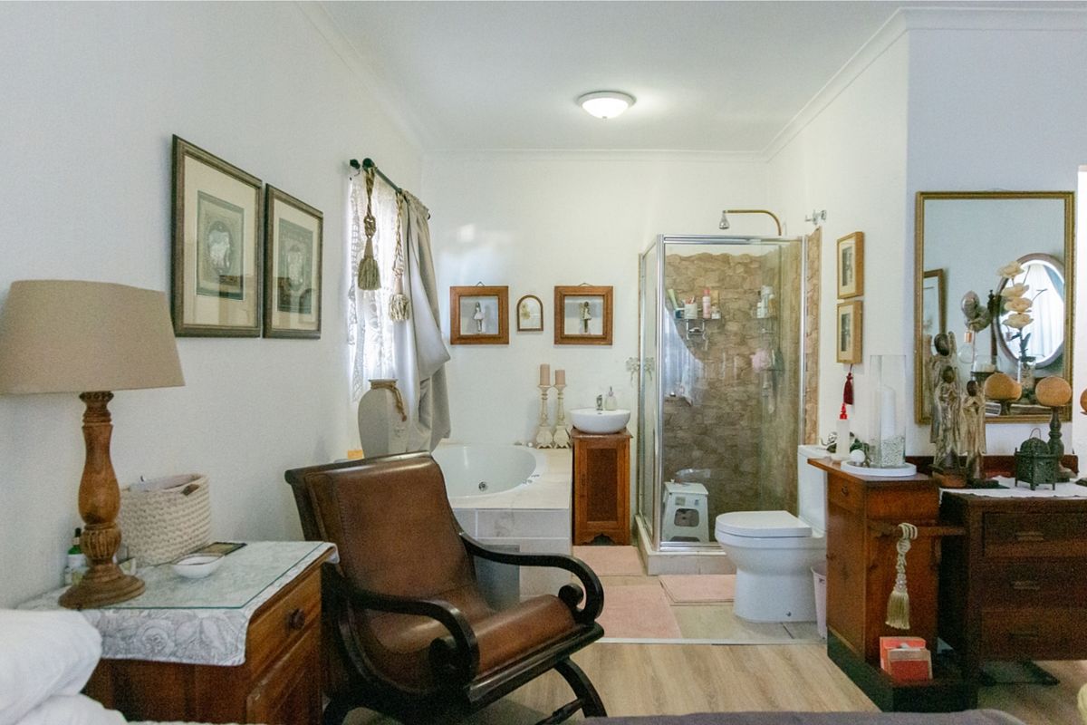 A functional bathroom featuring a built-in bathtub, a separate shower enclosure, a vanity sink, and a toilet with laminate flooring.
