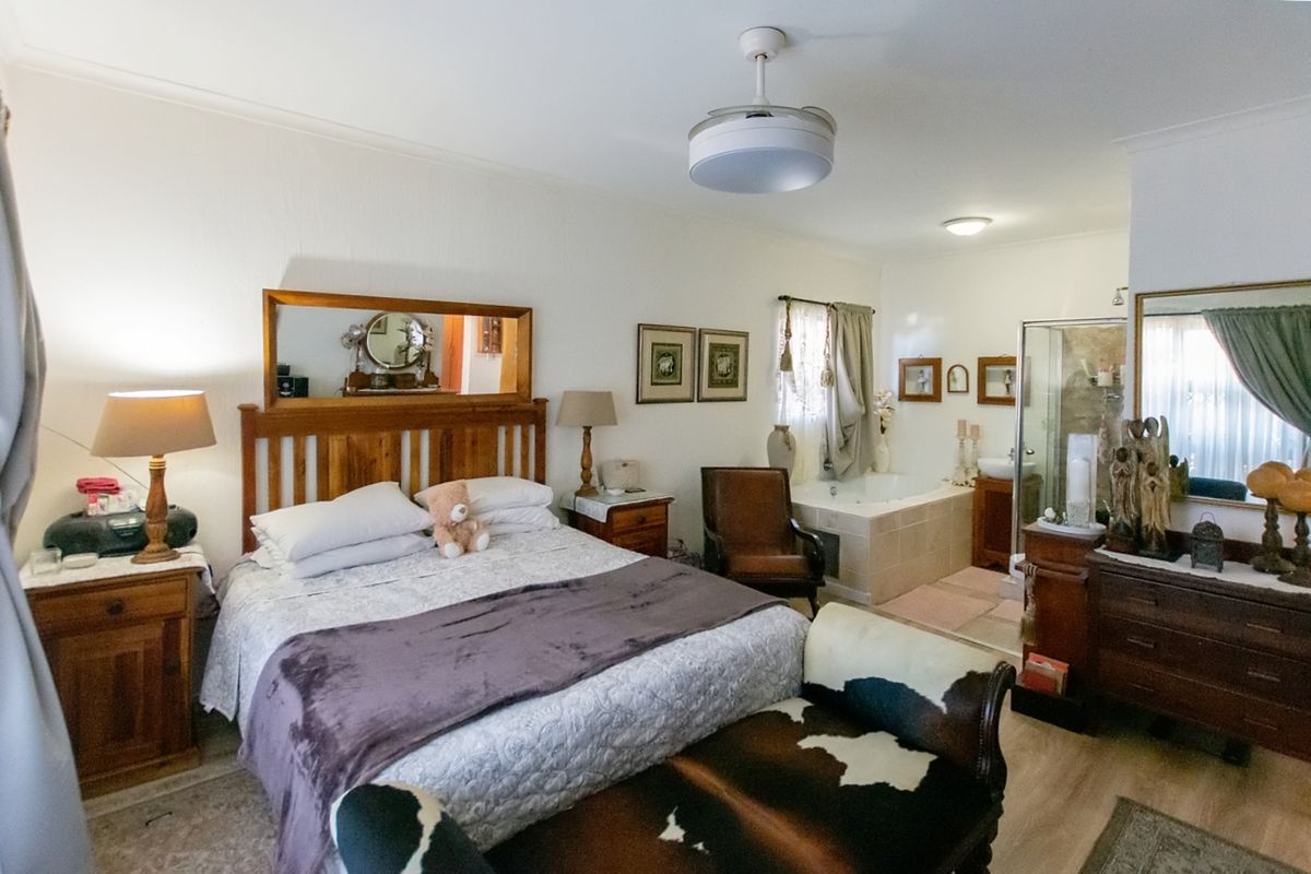 Spacious bedroom featuring an integrated en-suite bathroom with a built-in bathtub and glass shower enclosure, offering a functional and open layout.