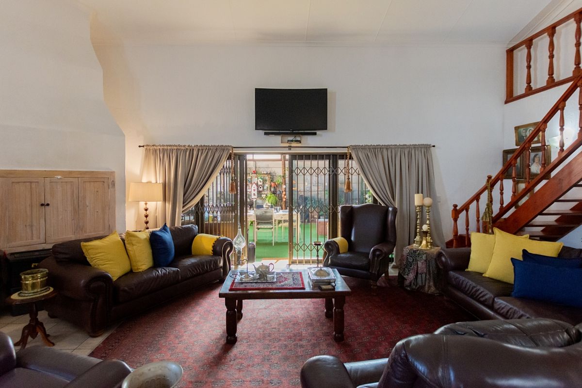 Spacious living room featuring high ceilings, a wooden staircase, and sliding glass doors that provide direct access to the outdoor patio area.