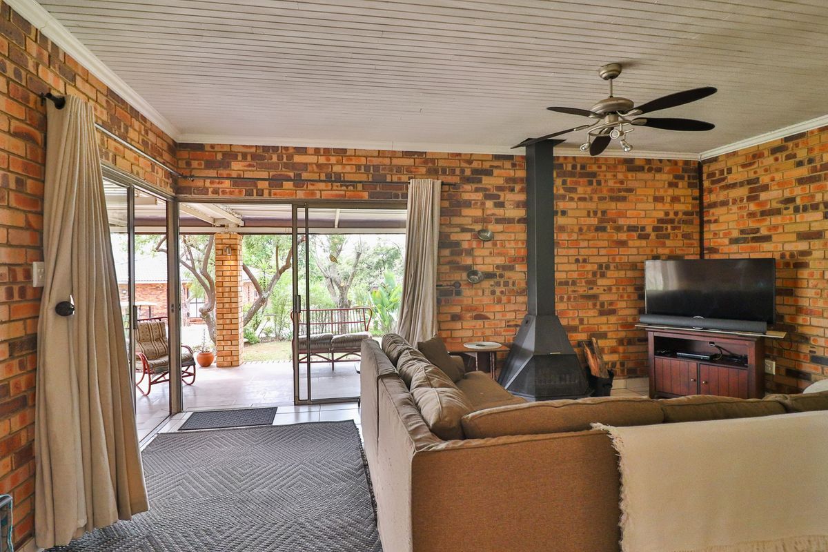 A cozy living room featuring exposed brick walls, a freestanding fireplace, and large sliding glass doors that open onto a covered patio area.