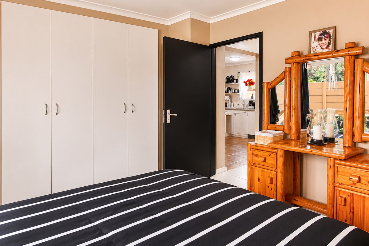A well-maintained bedroom featuring built-in cupboards and a view through to the kitchen area.