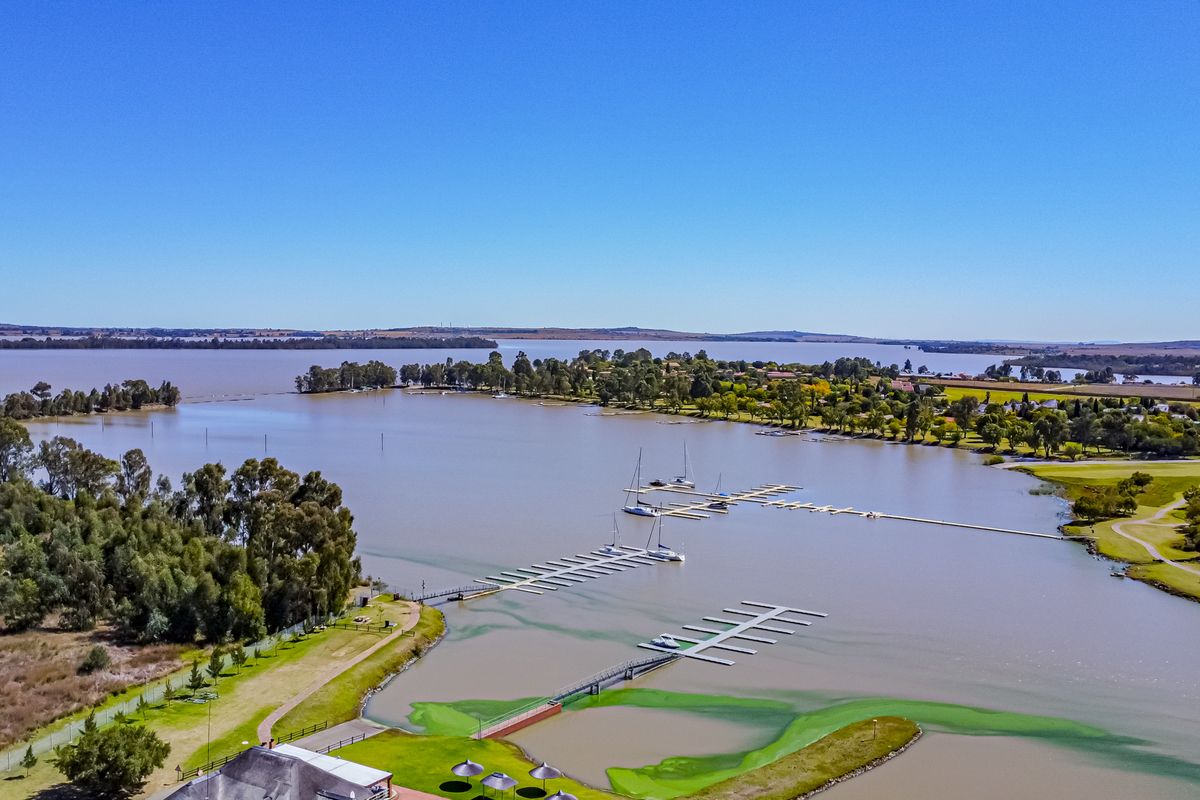 An aerial view of the estate featuring a large lake, marina, and boat jetties, showcasing the scenic waterfront location.