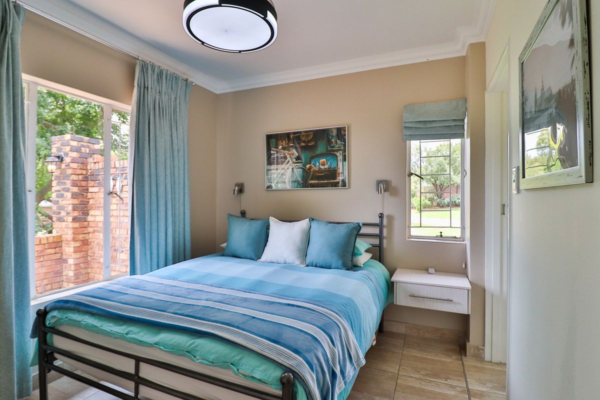 A well-maintained bedroom featuring tiled flooring, cove cornicing, and large windows that provide natural light and views of the garden.