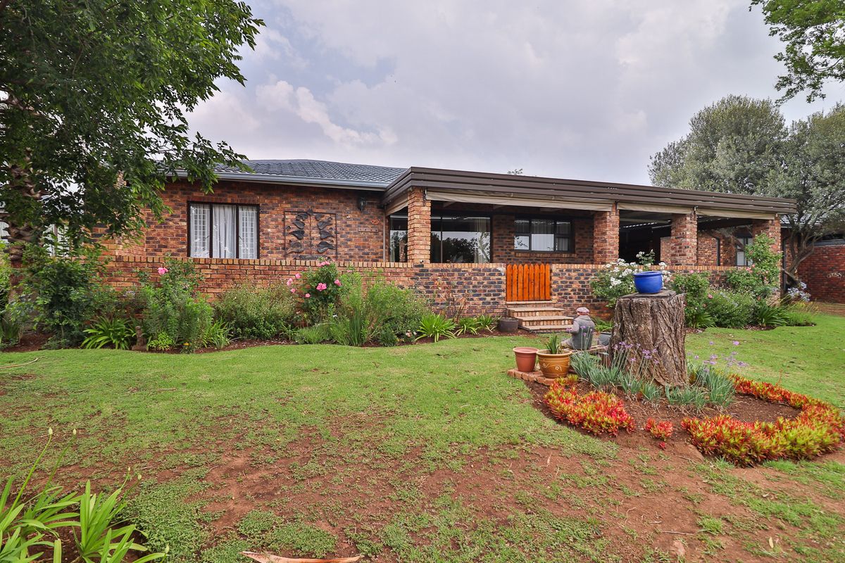 A well-maintained face brick cluster home featuring a spacious covered patio and a lush, established garden.