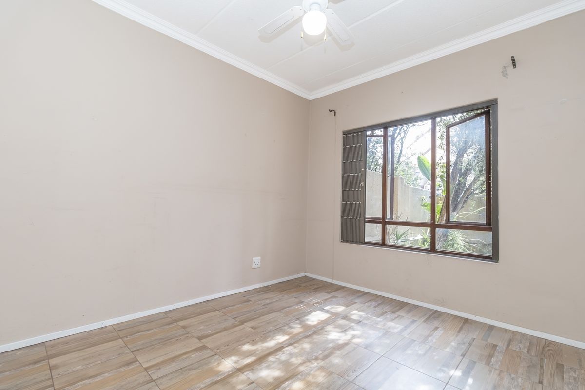 An empty bedroom featuring tiled flooring, a ceiling fan, and a large window with natural light.
