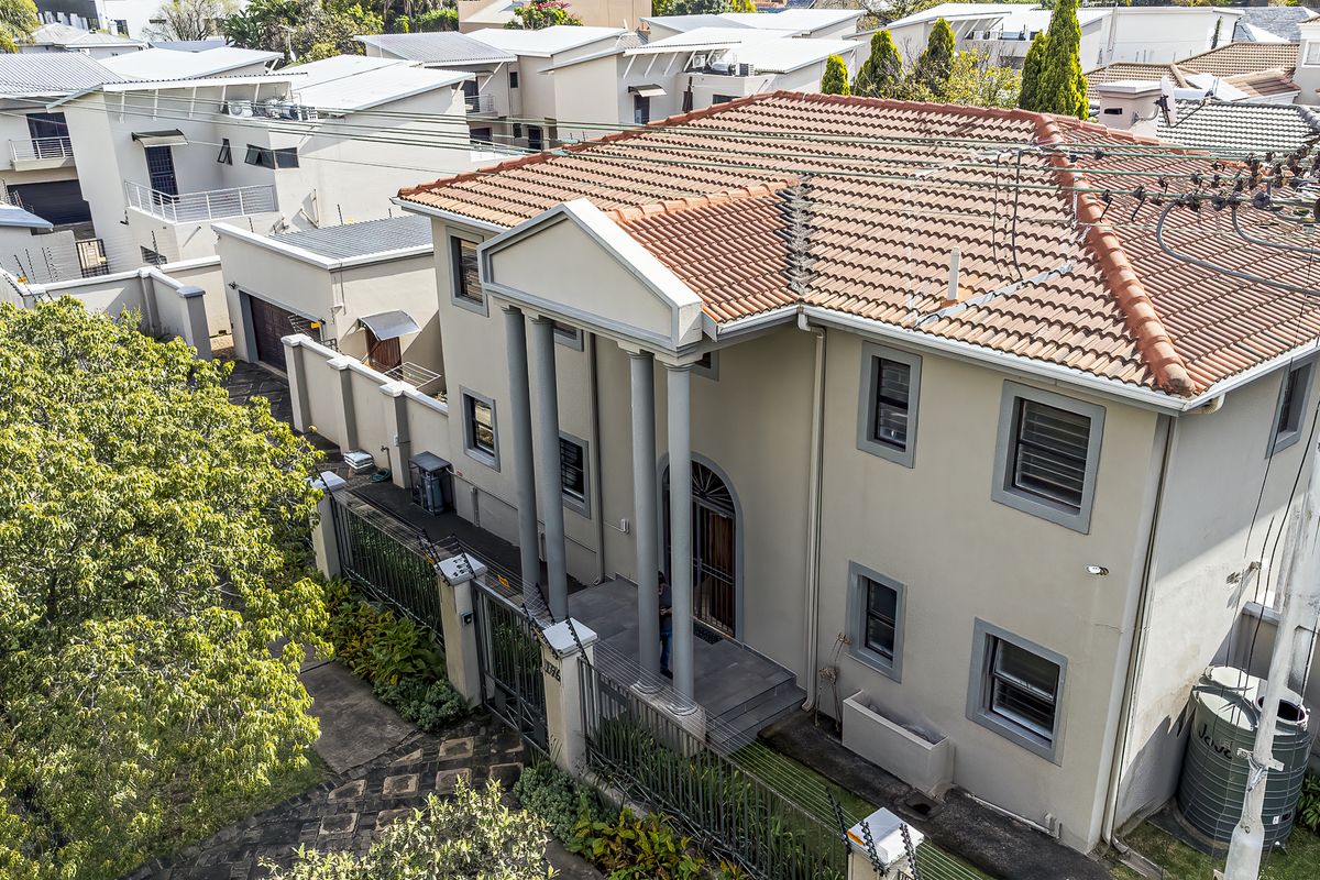Aerial view of a two-story residential property featuring a terracotta tiled roof, neoclassical entrance columns, and a secure perimeter fence.