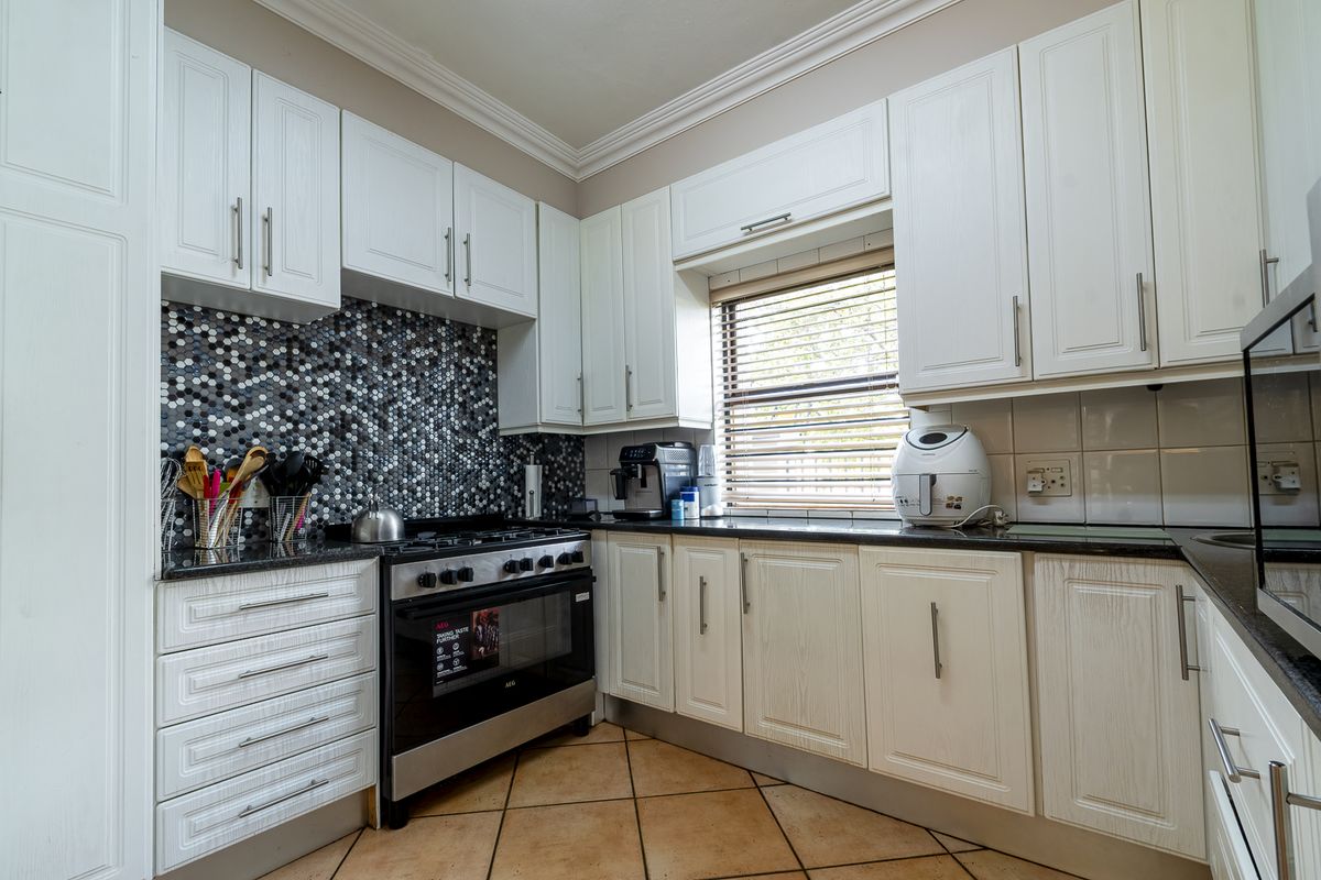 A well-maintained kitchen featuring white cabinetry, granite countertops, a mosaic tile backsplash, and a built-in gas stove with oven.