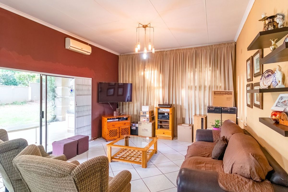 Spacious living room featuring tiled flooring, a split-system air conditioner, and large sliding glass doors providing direct access to the outdoor area.