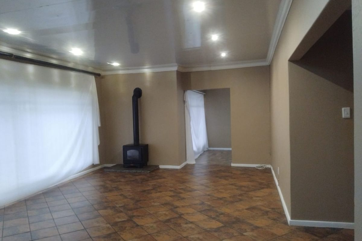 Spacious living area featuring tiled flooring, a freestanding fireplace, and recessed downlighting, offering a neutral canvas for interior design.