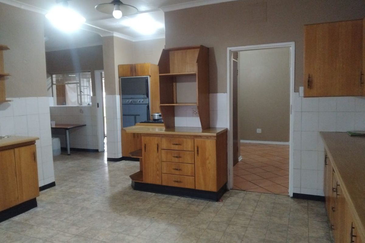 Spacious kitchen featuring dated wooden cabinetry, tiled splashbacks, and built-in appliances, offering a functional layout ready for modernization.
