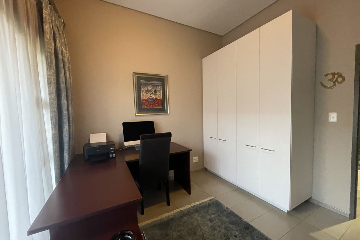A functional bedroom featuring built-in white cabinetry and tiled flooring, currently utilized as a home office space.