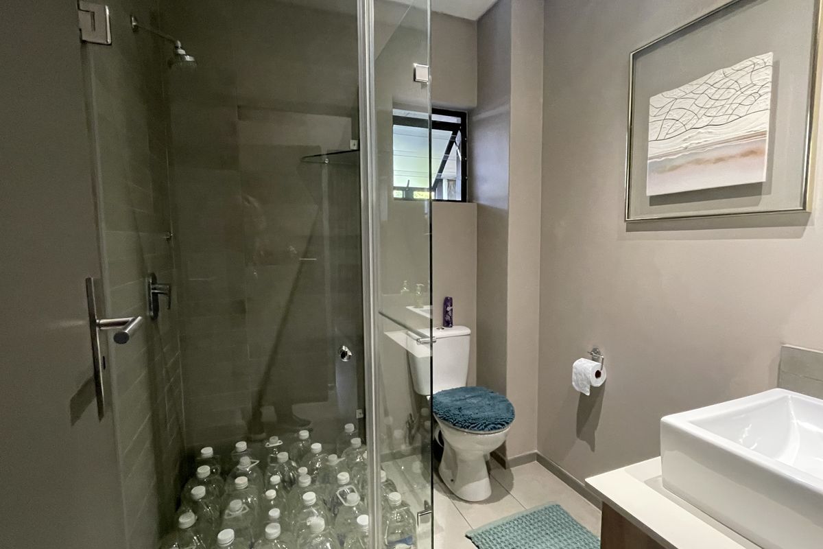 Modern bathroom featuring a glass-enclosed shower, a white ceramic toilet, and a contemporary vanity basin with neutral wall finishes.