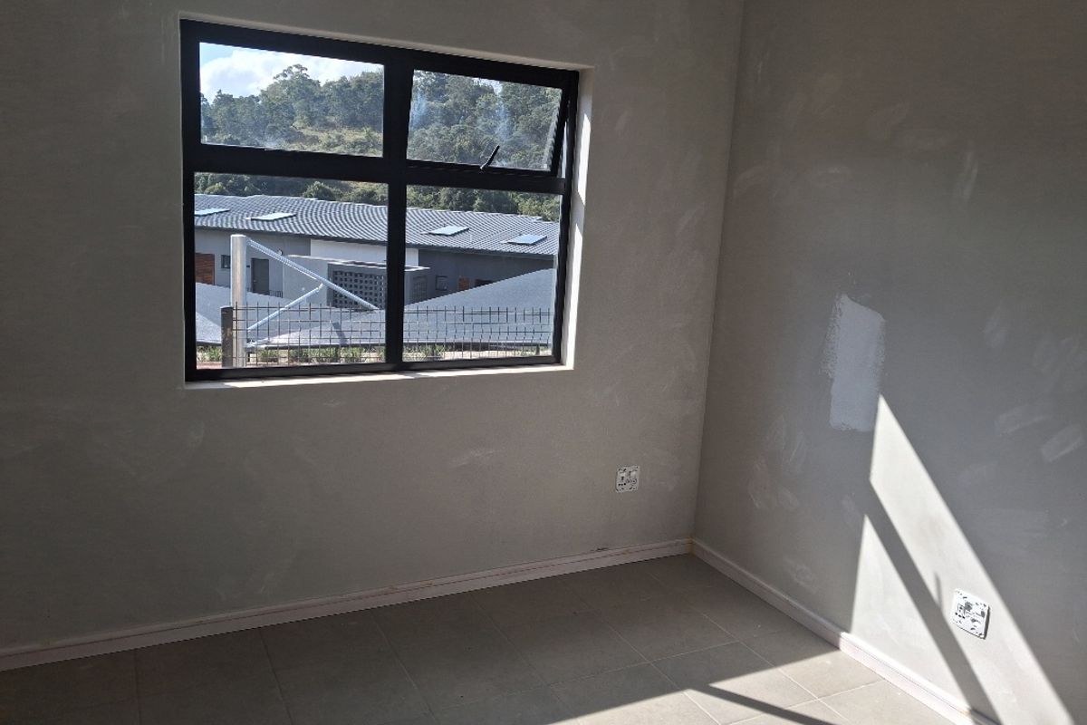 An unfinished bedroom interior featuring tiled flooring, aluminium window frames, and walls requiring final plastering and painting.