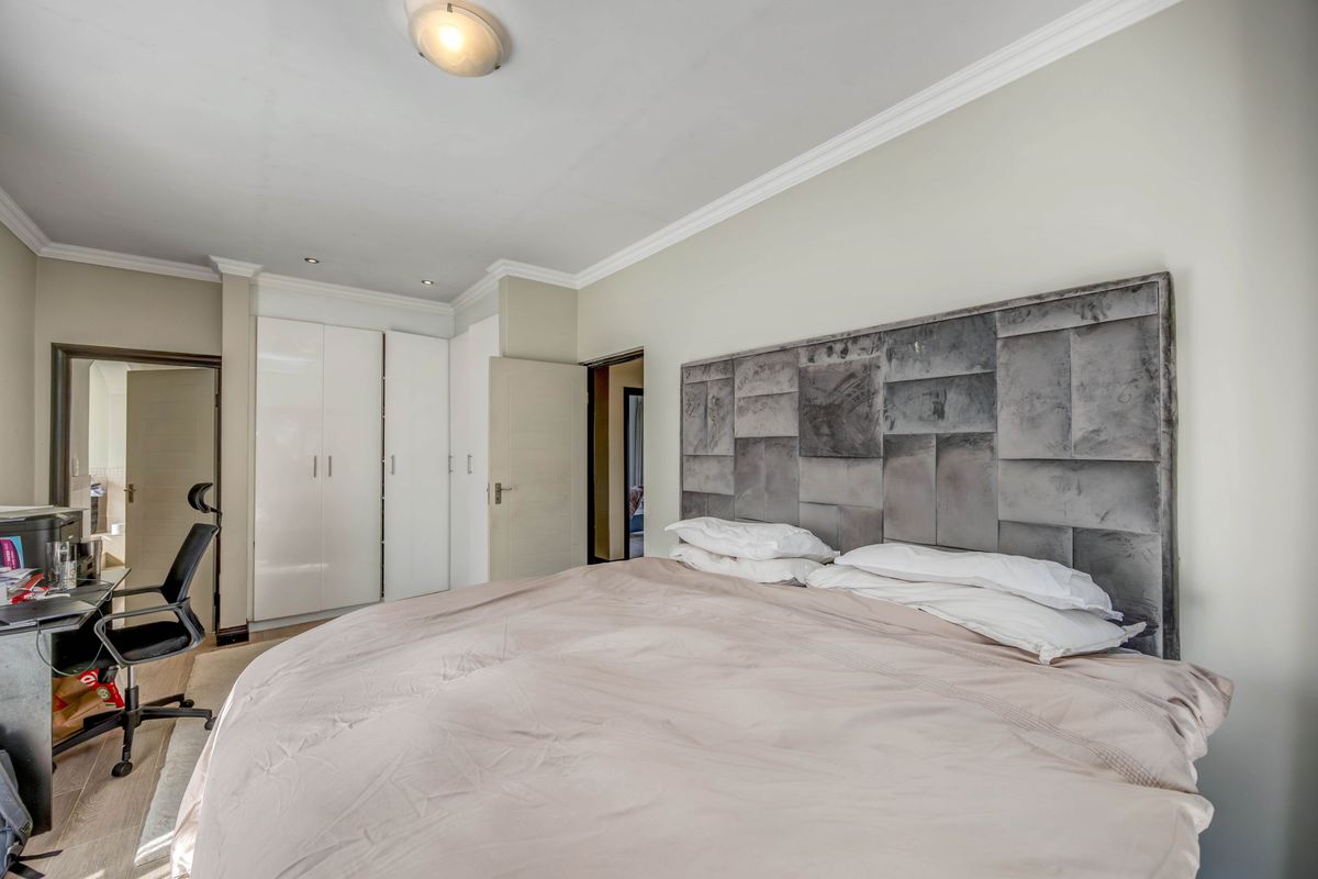 A well-lit bedroom featuring built-in cupboards, crown molding, and recessed ceiling lighting, providing a functional and comfortable living space.