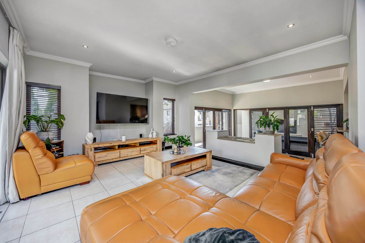 Spacious living room featuring tiled flooring, recessed lighting, crown molding, and large sliding glass doors leading to an outdoor area.