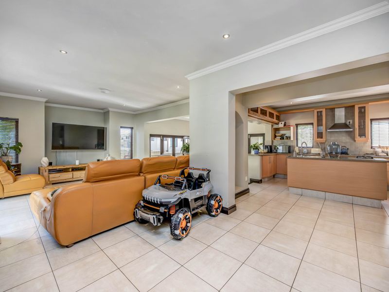 Spacious open-plan living area featuring tiled floors, recessed lighting, and a functional kitchen with built-in cabinetry and an extractor fan.