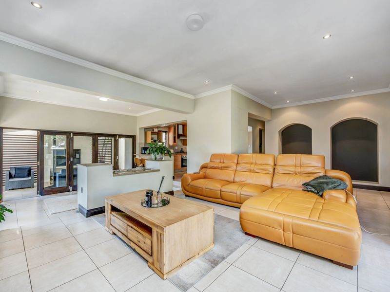 Spacious open-plan living area featuring ceramic floor tiles, recessed lighting, and architectural wall niches, seamlessly connecting to the kitchen and outdoor patio space.