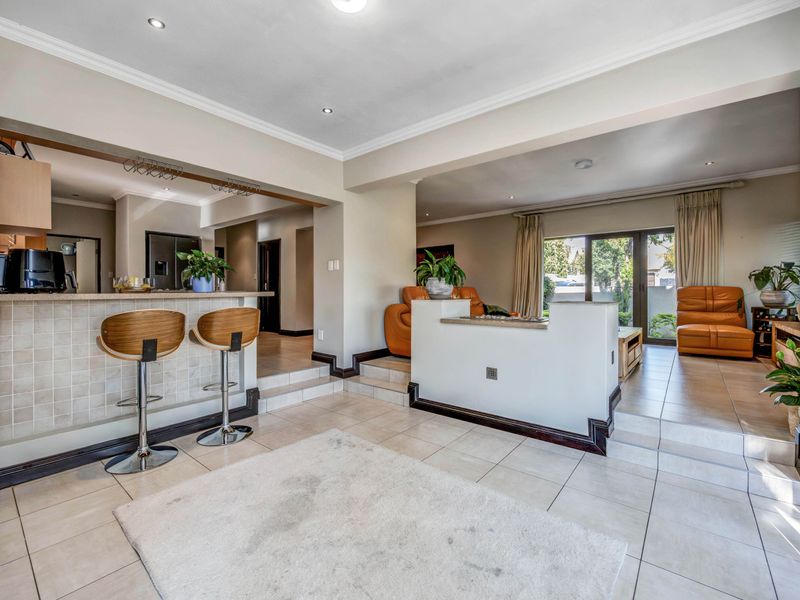 Spacious open-plan living area featuring a breakfast bar, split-level tiled flooring, and direct access to the outdoor space through sliding glass doors.