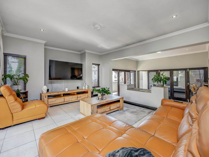 Spacious living room featuring tiled flooring, recessed lighting, crown molding, and large sliding glass doors leading to an outdoor area.