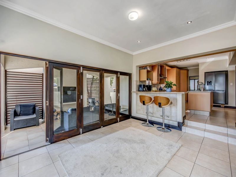 Open-plan living area featuring tiled floors, a breakfast bar, and large bi-fold doors providing seamless access to the outdoor patio space.
