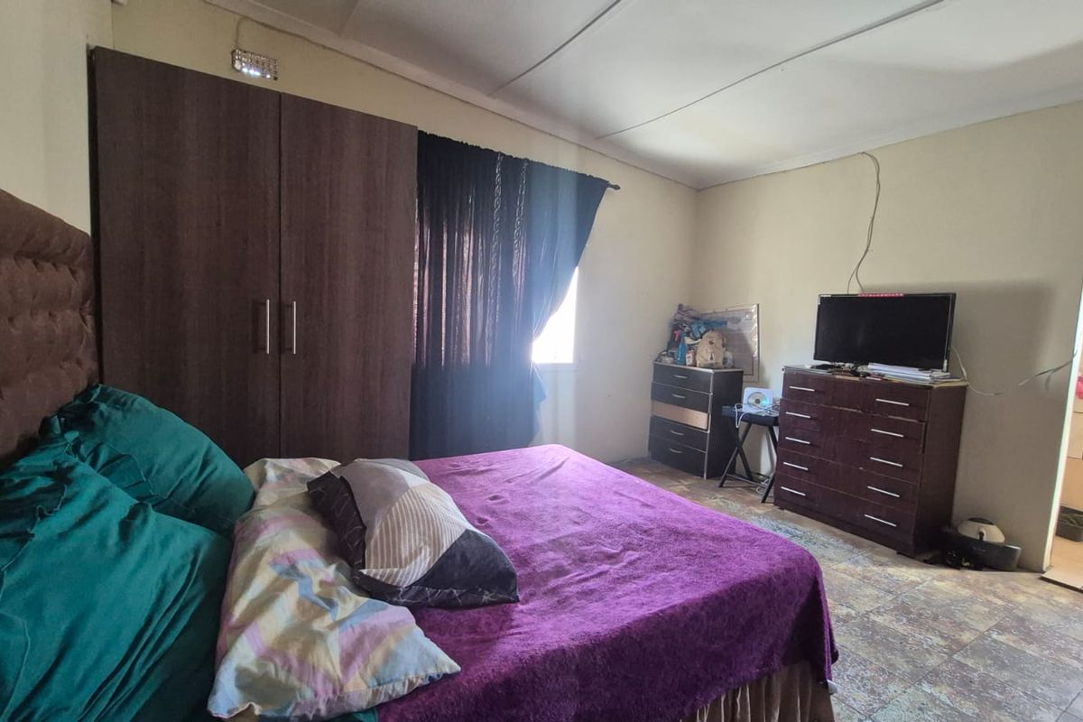 A bedroom featuring tiled flooring and a built-in wardrobe, with an adjacent en-suite bathroom area visible.