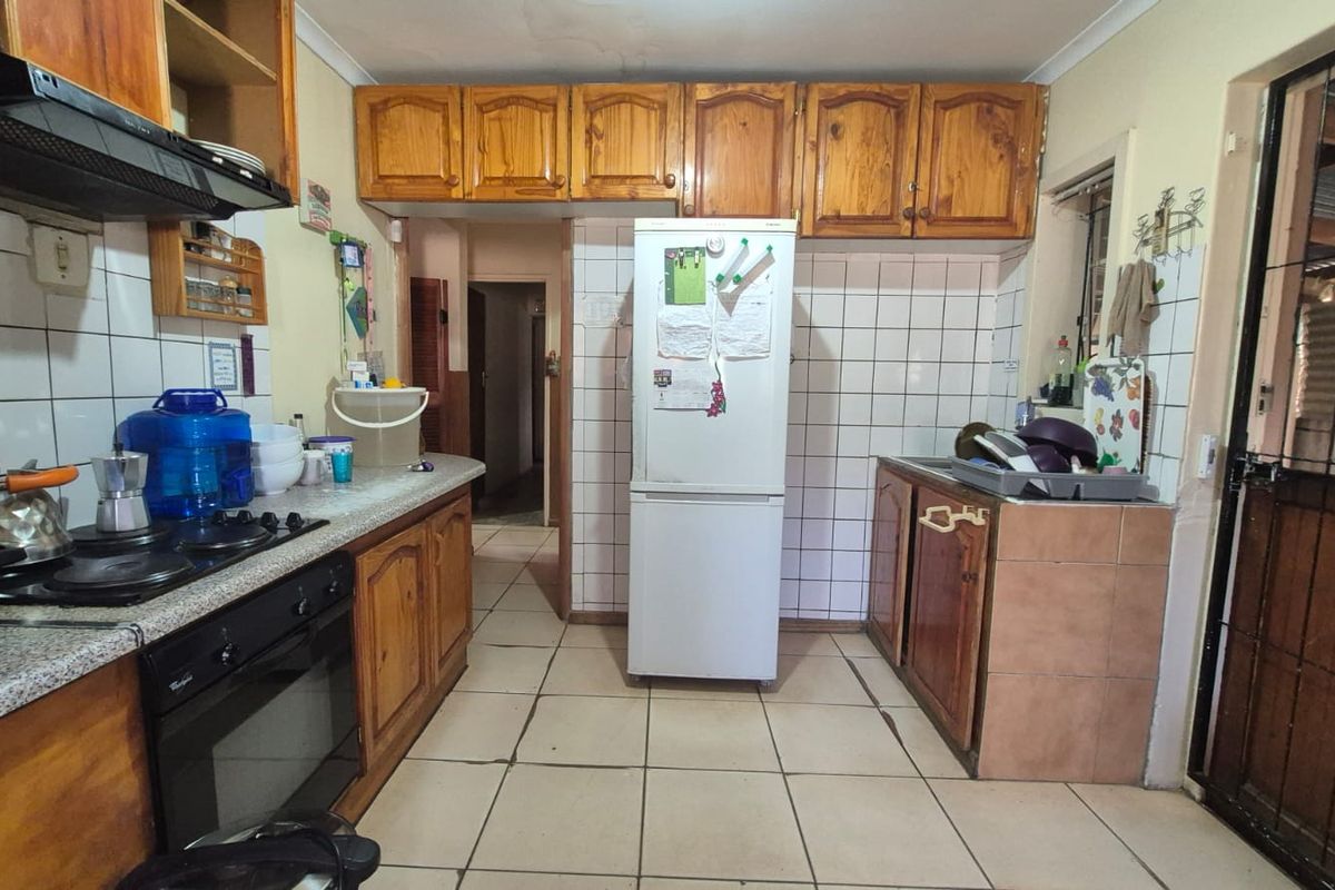 A functional kitchen featuring wooden cabinetry, tiled backsplash, and built-in cooking appliances, offering potential for a modern renovation.