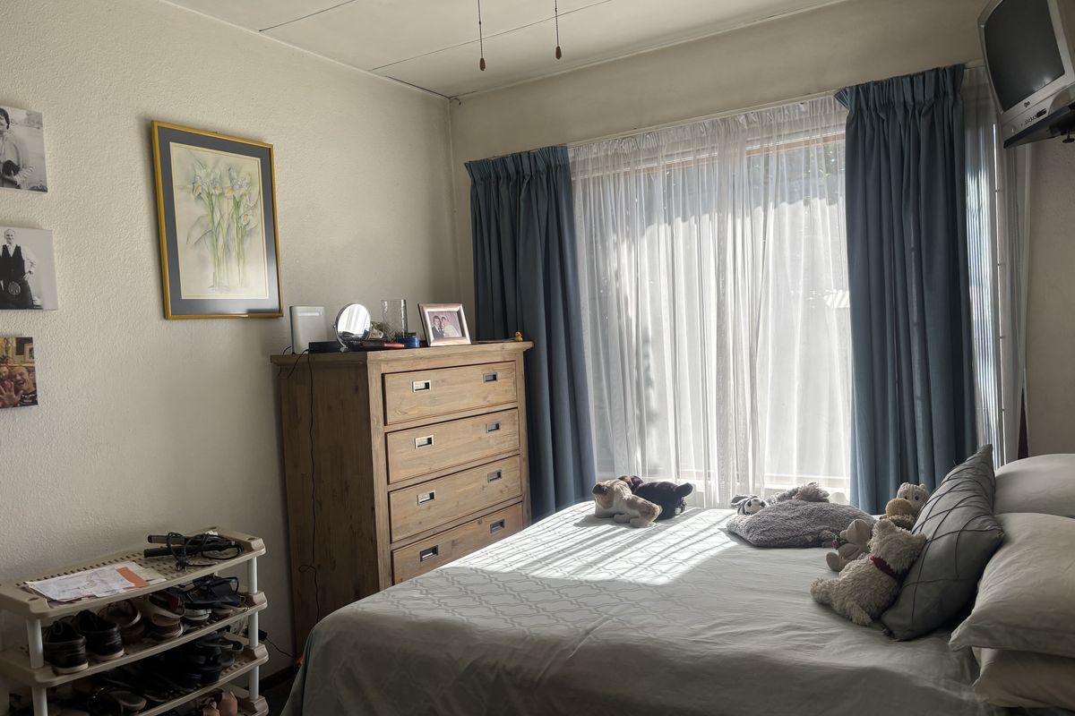 A bedroom featuring a large window with curtains and a ceiling fan, providing natural light and ventilation.